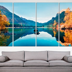 May include: A panoramic view of a mountain lake with a reflection of the surrounding trees and mountains in the water. The trees are a mix of green and yellow, indicating autumn. The water is a vibrant blue.