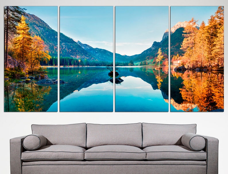 May include: A panoramic view of a mountain lake with a reflection of the surrounding trees and mountains in the water. The trees are a mix of green and yellow, indicating autumn. The water is a vibrant blue.