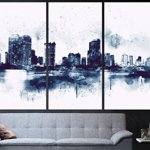 May include: A watercolor painting of a city skyline in shades of blue and white. The cityscape is reflected in the water below. The painting is divided into three panels.