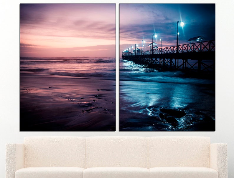 May include: Two-panel canvas art featuring coastal scenes. The left panel depicts a beach at sunset with pink and purple hues. The right panel shows a pier at night, illuminated by streetlights, with dark blue and teal tones.