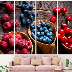 May include: Three waffle cones filled with different berries. The first cone is filled with blueberries, the second with raspberries, and the third with cherries. The cones are on a wooden background.