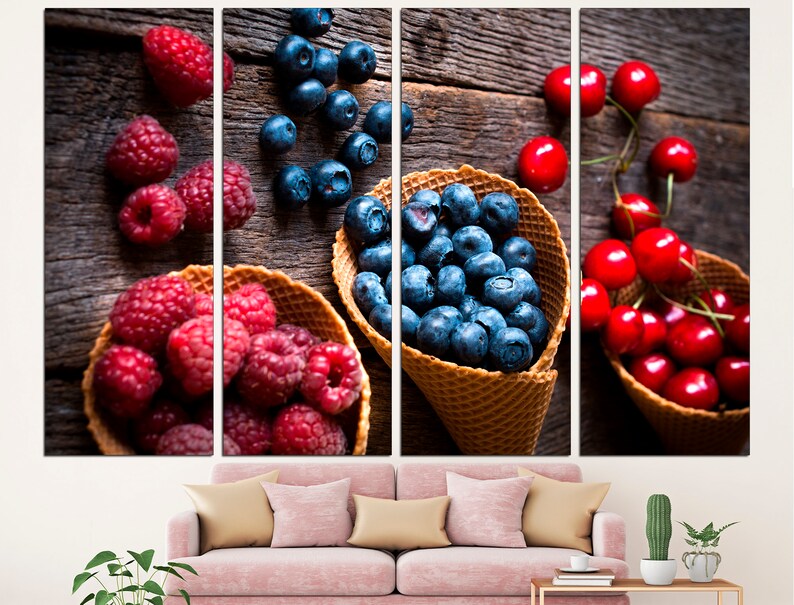 May include: Three waffle cones filled with different berries. The first cone is filled with blueberries, the second with raspberries, and the third with cherries. The cones are on a wooden background.