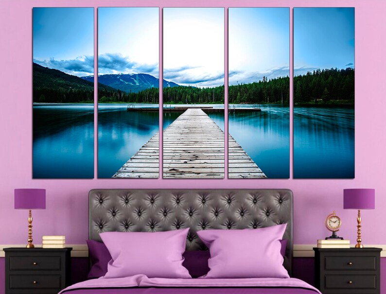 May include: A five-panel canvas print depicting a wooden dock extending into a still lake with a mountain range in the background. The lake is a vibrant blue, and the sky is a soft blue with white clouds. The dock is made of weathered wood planks.