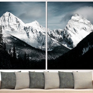 Puede incluir: Una impresi&oacute;n en lienzo dividida en dos partes que presenta una vista panor&aacute;mica de dos picos de monta&ntilde;a cubiertos de nieve que se elevan sobre un bosque verde oscuro. Las monta&ntilde;as est&aacute;n cubiertas de nieve blanca y el cielo es azul claro con algunas nubes.