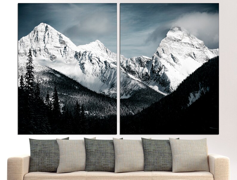 Puede incluir: Una impresi&oacute;n en lienzo dividida en dos partes que presenta una vista panor&aacute;mica de dos picos de monta&ntilde;a cubiertos de nieve que se elevan sobre un bosque verde oscuro. Las monta&ntilde;as est&aacute;n cubiertas de nieve blanca y el cielo es azul claro con algunas nubes.