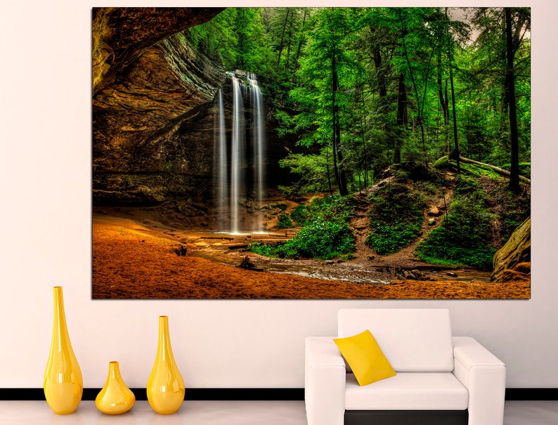 Peut inclure: Une grande toile imprim&eacute;e repr&eacute;sentant une cascade dans une for&ecirc;t luxuriante. L'eau tombe dans un bassin, entour&eacute;e d'arbres verts. La sc&egrave;ne se d&eacute;roule dans une alc&ocirc;ve rocheuse, avec une lumi&egrave;re chaude. Des vases jaunes sont au premier plan.