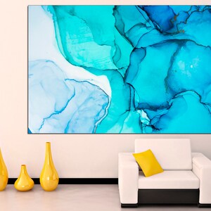 May include: Abstract art print featuring swirling blue and white paint in a modern style. The print is displayed on a white wall above a white couch with a yellow pillow.