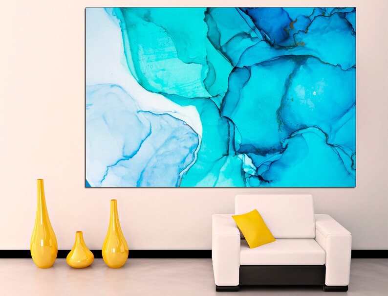May include: Abstract art print featuring swirling blue and white paint in a modern style. The print is displayed on a white wall above a white couch with a yellow pillow.