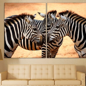 Pode incluir: Tr&ecirc;s zebras est&atilde;o juntas em uma &aacute;rea arenosa. As zebras est&atilde;o olhando para a c&acirc;mera e suas cabe&ccedil;as se tocam. As zebras t&ecirc;m listras pretas e brancas.