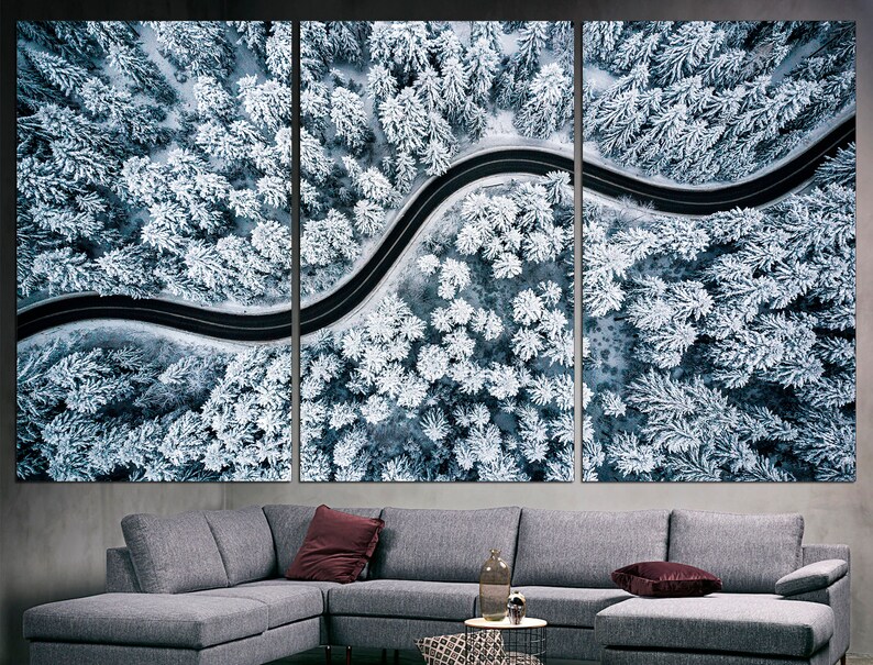 以下が含まれることがあります： 雪に覆われた森の中を蛇行する道路の航空写真。木々は厚い雪に覆われ、道路は白い風景の中に暗い線として見える。