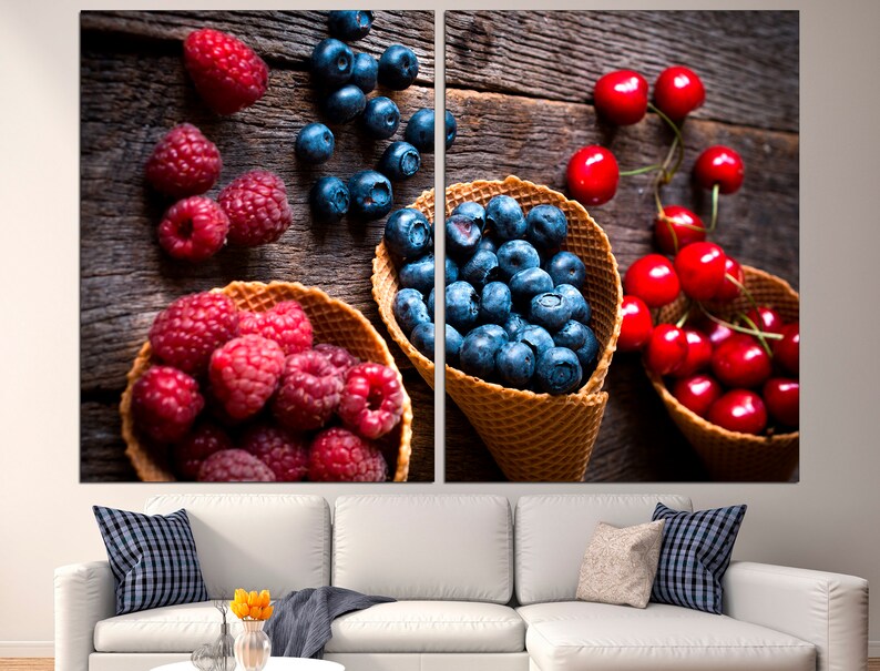 May include: A rustic wooden background with three waffle cones filled with blueberries, raspberries, and cherries. The cones are arranged in a row, with the blueberries in the center, the raspberries on the left, and the cherries on the right.