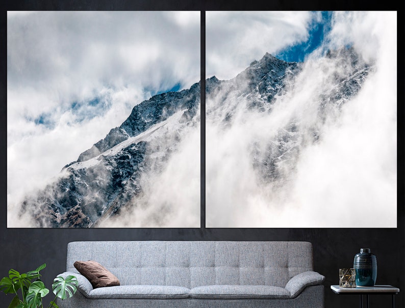 Puede incluir: Un pico de monta&ntilde;a nevado parcialmente oculto por nubes blancas contra un cielo azul.