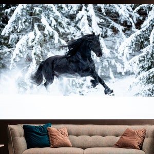 Op de afbeelding: Een zwart paard rent door een besneeuwd bos. Het paard is in beweging, met zijn manen en staart die in de wind wapperen. De met sneeuw bedekte bomen cre&euml;ren een winters decor.
