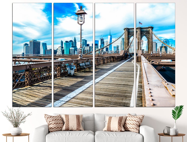 May include: A panoramic view of the Brooklyn Bridge in New York City. The bridge is a suspension bridge with a wooden walkway and a view of the city skyline in the background. The sky is blue with white clouds.