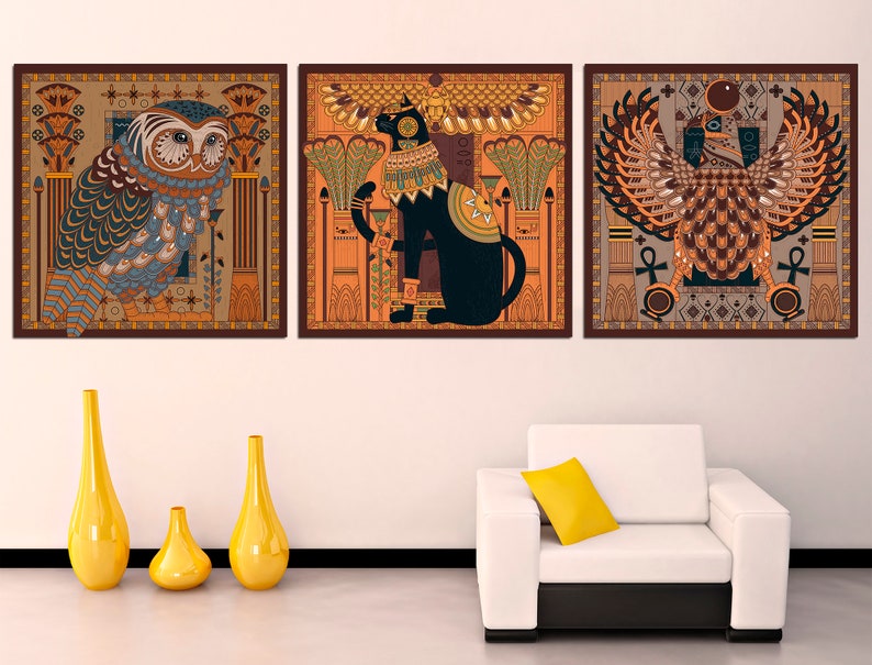 May include: Three framed prints with an Egyptian theme. The left print features a blue and brown owl with intricate details. The center print features a black cat with a gold collar and a crown. The right print features a brown and gold bird with a crown and an ankh.
