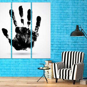 May include: A black and white handprint art print on a white background, displayed on a blue brick wall with a black and white striped armchair and a black floor lamp.
