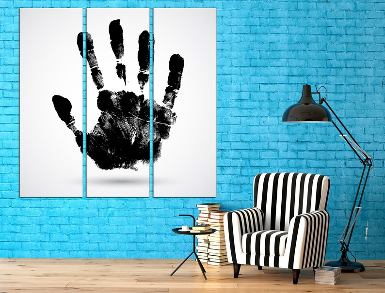 May include: A black and white handprint art print on a white background, displayed on a blue brick wall with a black and white striped armchair and a black floor lamp.