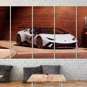 May include: A white Lamborghini Aventador SVJ Roadster parked in an alleyway with a brick wall in the background. The car has a black interior and gold wheels.