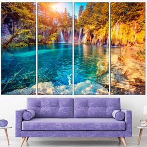 May include: A multi-panel canvas print featuring a scenic landscape with a turquoise lake, waterfalls, and lush green trees. The image is divided into three panels, creating a panoramic view of the natural beauty.
