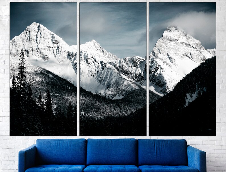 Puede incluir: Una vista panor&aacute;mica de monta&ntilde;as cubiertas de nieve con un bosque oscuro en primer plano. Las monta&ntilde;as est&aacute;n cubiertas de nieve blanca y el cielo es azul claro con algunas nubes.