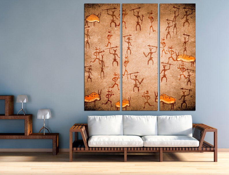 May include: A three-panel canvas print depicting a cave painting style image of stick figures hunting animals. The figures are brown and orange, and the background is a textured beige.