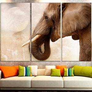 May include: A close-up of an elephant's face, with a large ear and trunk, against a light brown background.