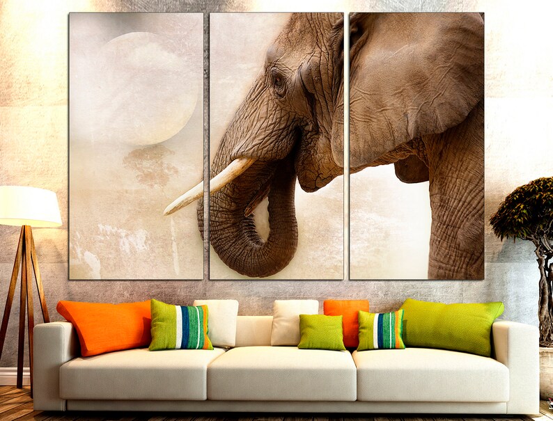 May include: A close-up of an elephant's face, with a large ear and trunk, against a light brown background.