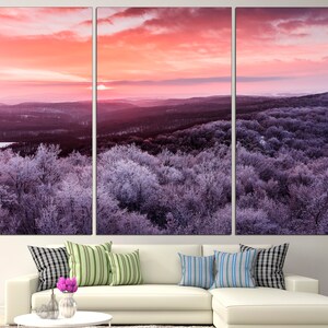 May include: A panoramic view of a snow-covered forest at sunrise. The sky is a vibrant pink and orange, with wispy clouds. The trees are covered in a layer of frost, giving them a silvery appearance.