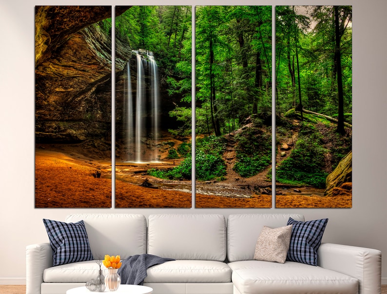 Peut inclure: Impression sur toile en plusieurs panneaux repr&eacute;sentant une cascade paisible se d&eacute;versant dans un bassin, entour&eacute;e d'arbres verts luxuriants. L'&oelig;uvre capture la beaut&eacute; naturelle d'un paysage forestier, avec des tons chauds de brun et d'orange au premier plan.