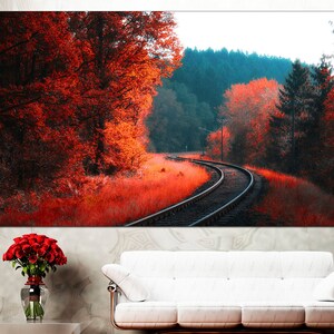K&ouml;nnte beinhalten: Ein Landschaftsfoto von einem Bahngleis, das sich durch einen Wald im Herbst schl&auml;ngelt. Die B&auml;ume sind in leuchtenden Rot- und Oranget&ouml;nen gehalten, und das Gleis ist von hohem Gras umgeben.