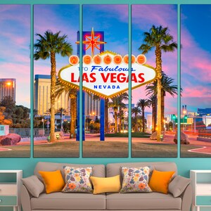 May include: A five-panel canvas print of the iconic "Welcome to Fabulous Las Vegas" sign at dusk. The sign is white with red and yellow accents, set against a vibrant pink and blue sky. Palm trees and city lights frame the sign.