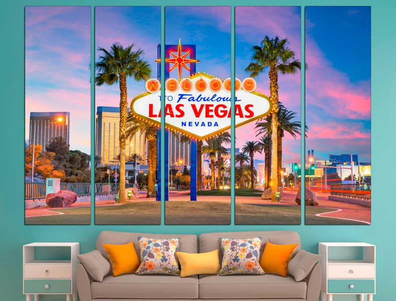 May include: A five-panel canvas print of the iconic "Welcome to Fabulous Las Vegas" sign at dusk. The sign is white with red and yellow accents, set against a vibrant pink and blue sky. Palm trees and city lights frame the sign.