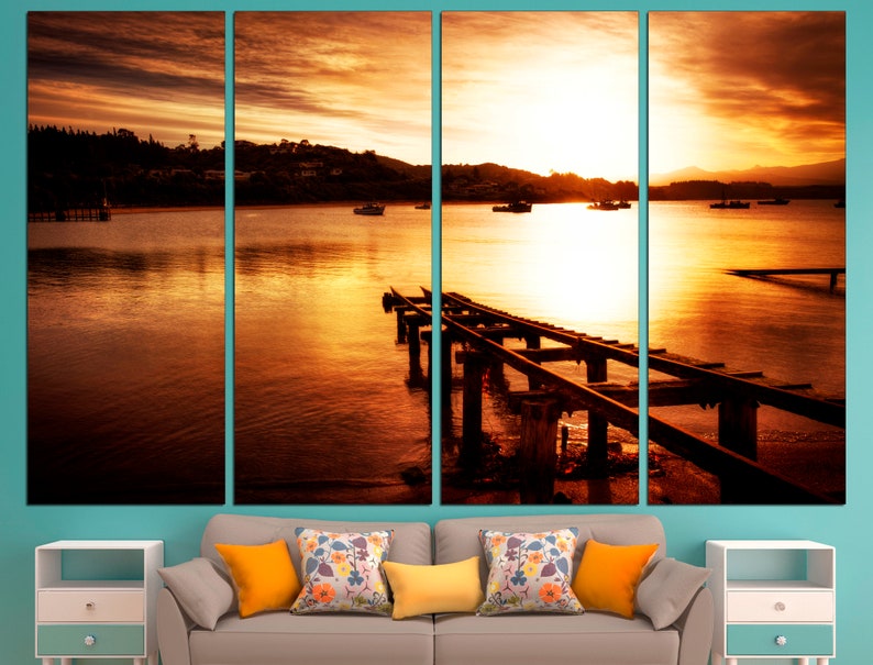 May include: A sunset over a body of water with a wooden pier extending into the water. The sky is a vibrant orange and yellow, and the water is a calm, reflective surface.