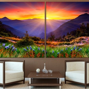 May include: A split canvas print of a mountain landscape with a vibrant sunset sky. The foreground features a field of wildflowers in shades of purple, green, and orange. The mountains are layered in shades of blue and purple, with a golden glow from the setting sun.