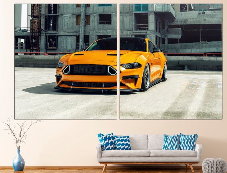 May include: A bright yellow Ford Mustang sports car parked in a concrete car park. The car is facing the camera and has a black grille and black wheels.