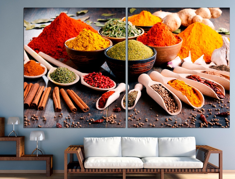 May include: A variety of spices in bowls and spoons, including red chili powder, turmeric, coriander, and cinnamon sticks. The spices are arranged on a wooden surface.