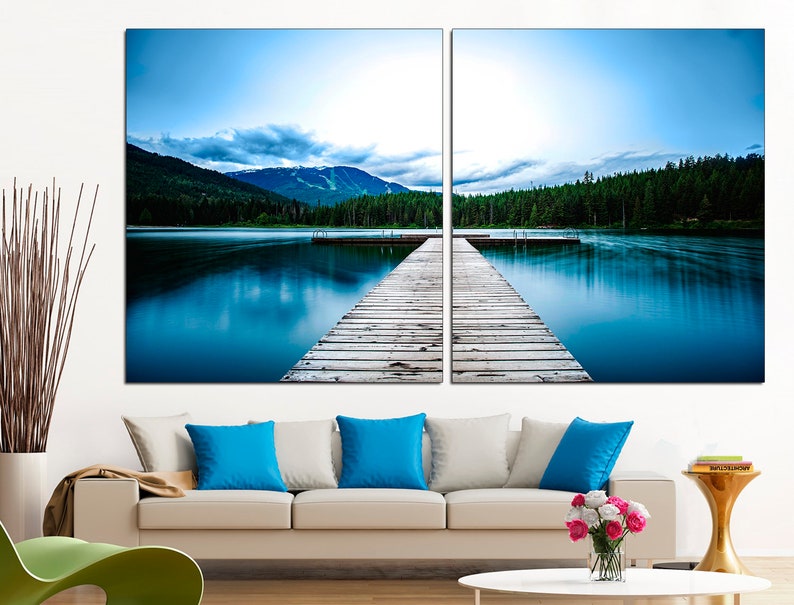May include: A split canvas print of a wooden dock extending into a still blue lake with a mountain range in the background.