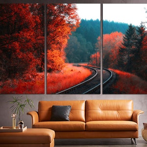 K&ouml;nnte beinhalten: Ein Triptychon-Leinwanddruck mit einer malerischen Landschaft, auf der sich ein Bahngleis durch einen Wald schl&auml;ngelt. Die B&auml;ume sind in Rot- und Oranget&ouml;nen gehalten und schaffen eine lebendige Herbstszene.