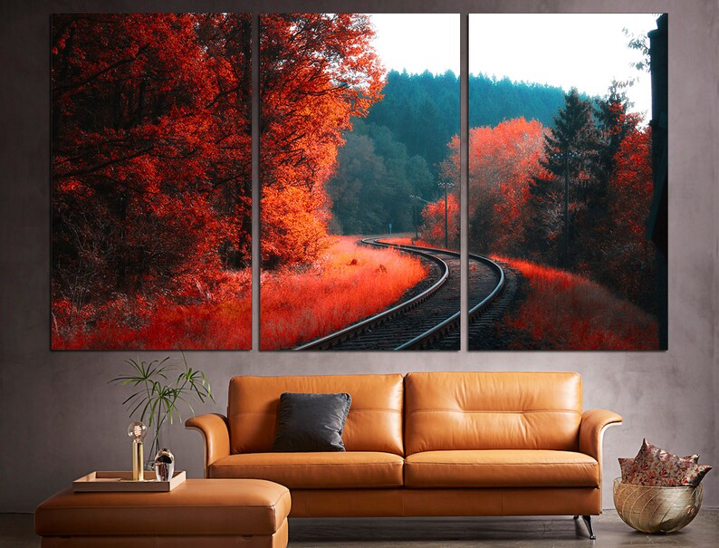 K&ouml;nnte beinhalten: Ein Triptychon-Leinwanddruck mit einer malerischen Landschaft, auf der sich ein Bahngleis durch einen Wald schl&auml;ngelt. Die B&auml;ume sind in Rot- und Oranget&ouml;nen gehalten und schaffen eine lebendige Herbstszene.