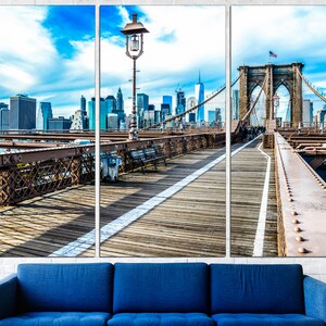 May include: A panoramic view of the Brooklyn Bridge in New York City. The bridge is a suspension bridge with a wooden walkway and a view of the city skyline in the background. The sky is blue with white clouds.