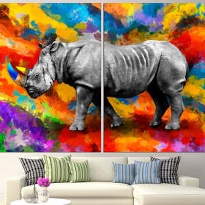 May include: A black and white rhinoceros with a blue and yellow horn stands on a colorful abstract background. The background is a mix of red, orange, yellow, purple, and blue.