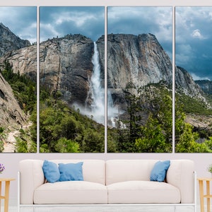 May include: A panoramic view of a waterfall cascading down a rocky cliff face in Yosemite National Park. Lush green trees and a cloudy sky complete the scene.