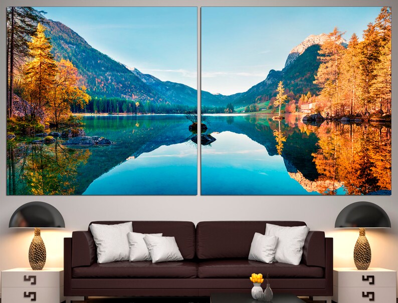 May include: A panoramic view of a lake surrounded by mountains with fall foliage reflected in the water.