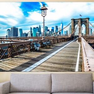May include: A view from the Brooklyn Bridge walkway looking towards the Manhattan skyline. The bridge is made of steel and has a wooden walkway. The sky is blue with white clouds.