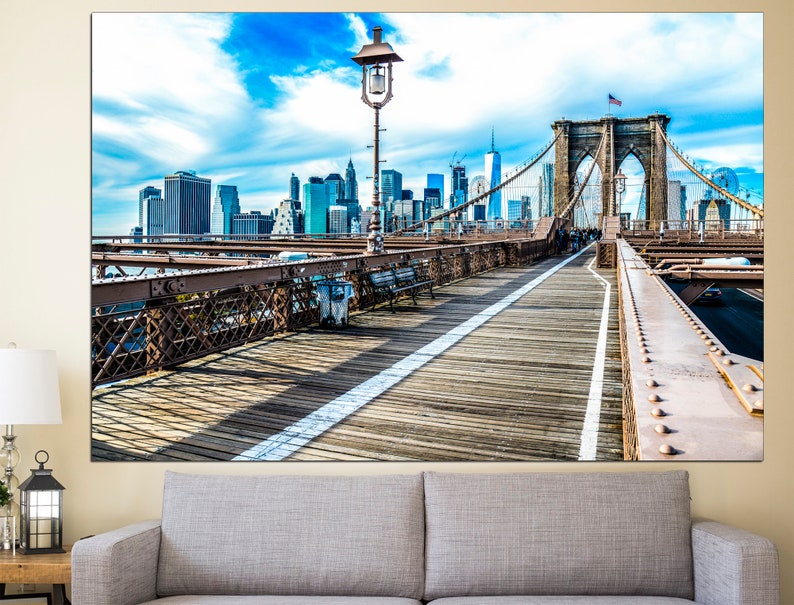 May include: A view from the Brooklyn Bridge walkway looking towards the Manhattan skyline. The bridge is made of steel and has a wooden walkway. The sky is blue with white clouds.
