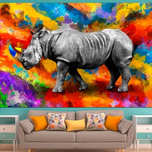May include: A black and white rhinoceros with a colorful horn stands on a colorful abstract background. The background is a mix of bright colors, including red, orange, yellow, green, blue, and purple.