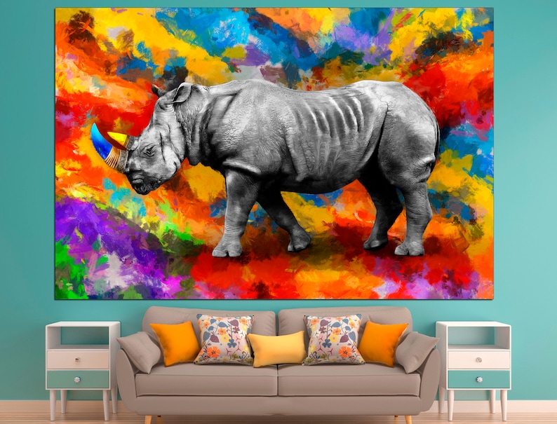 May include: A black and white rhinoceros with a colorful horn stands on a colorful abstract background. The background is a mix of bright colors, including red, orange, yellow, green, blue, and purple.