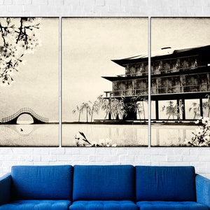 May include: A black and white triptych canvas print depicting a traditional Japanese house with a bridge and cherry blossoms. The house is on stilts over a body of water. The image has a vintage, faded look.