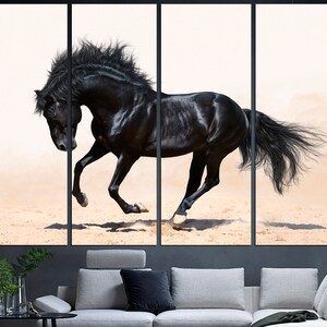 May include: A black horse runs across a sandy surface with its mane and tail flowing in the wind. The horse is in sharp focus against a white background.
