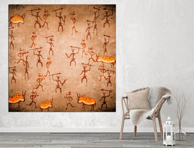 May include: A brown canvas print with an orange and brown cave painting of stick figures hunting animals. The figures are holding spears and the animals are bison.